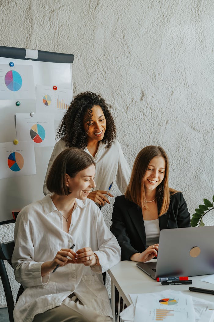 Mastering the First Impression: Your intriguing post title goes here Three businesswomen collaborate with graphs and a laptop in a modern office setting.